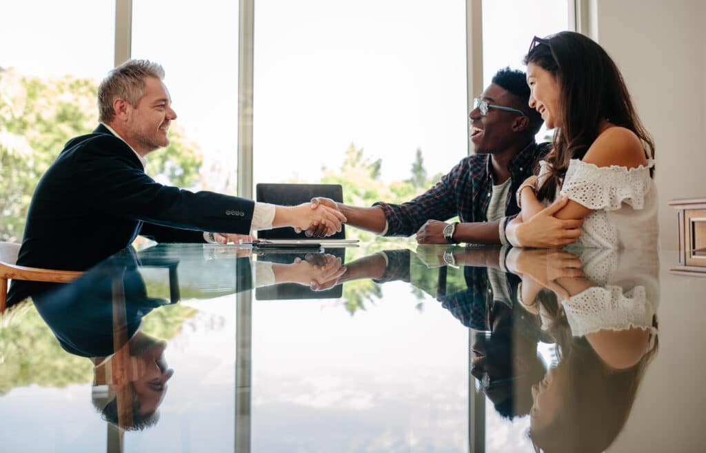 Couple shaking hands with a leasing agent in a big room